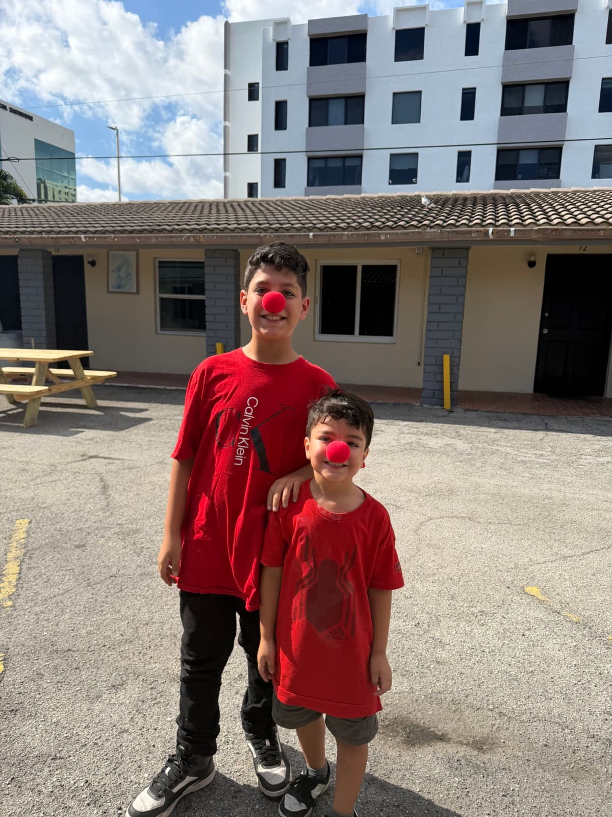 Two smiling kids wearing red clown noses at a Miami community event